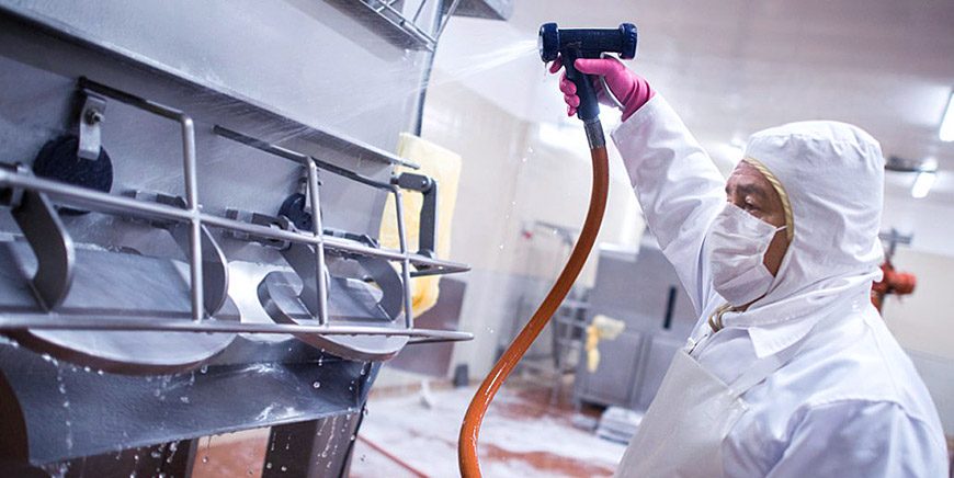 Protective-suit technician cleaning food equipment