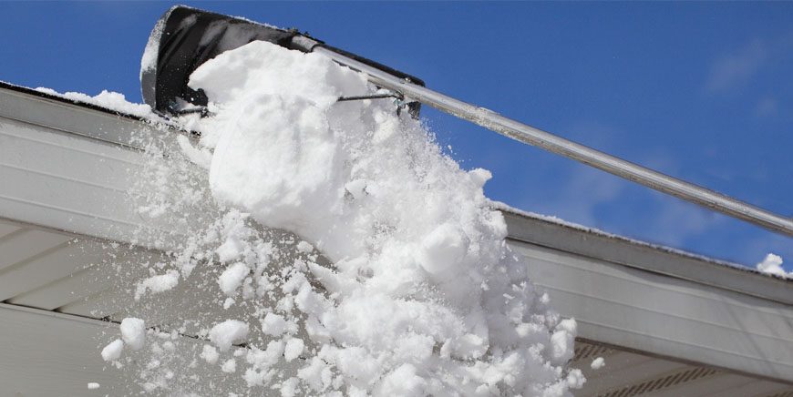 Manual snow removal at the edge of a roof