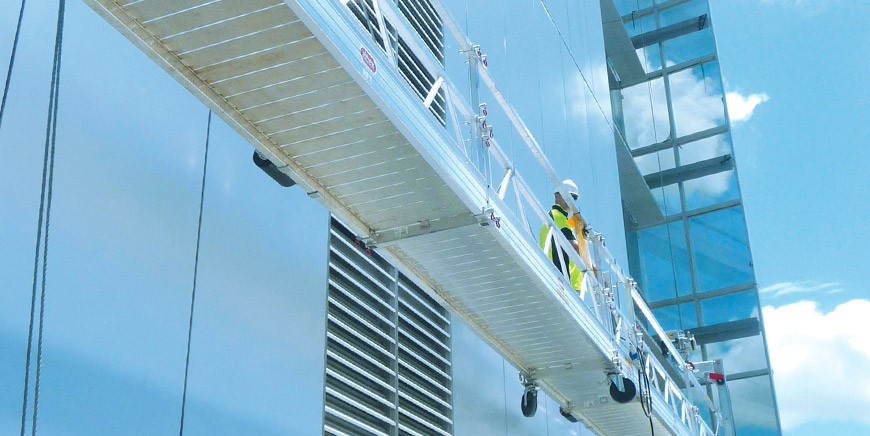 Rope-access technician cleaning building windows